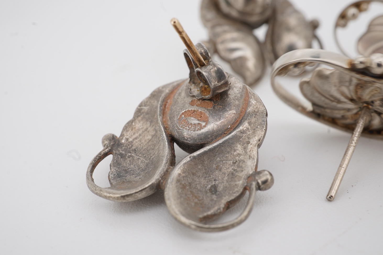 Two pairs of Georg Jensen sterling ear studs, one pair of leaf and berry design, 18mm and flower head form, design no. 52, lacking butterflies.